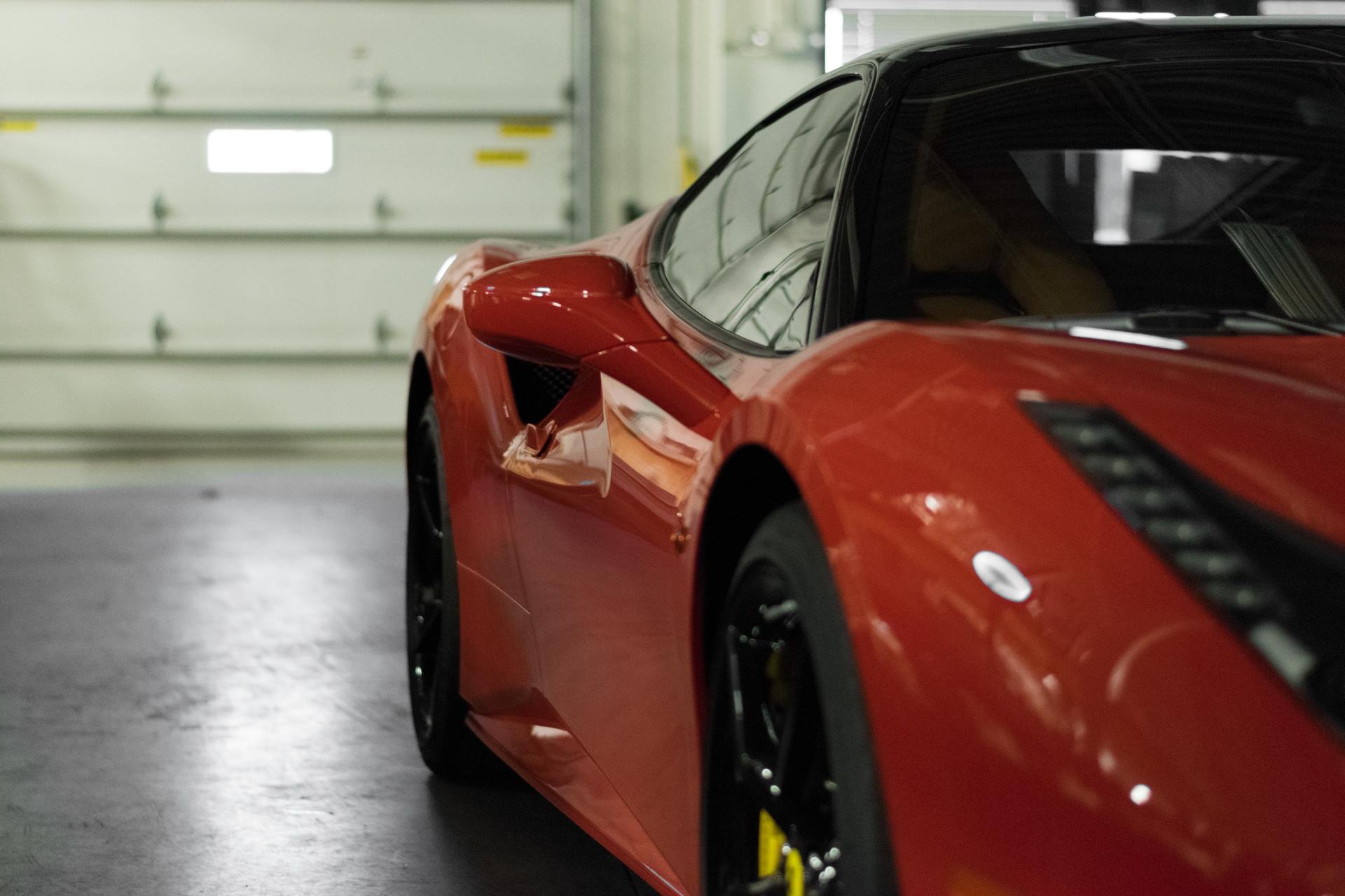 Red Ferrari sports car parked inside a garage.