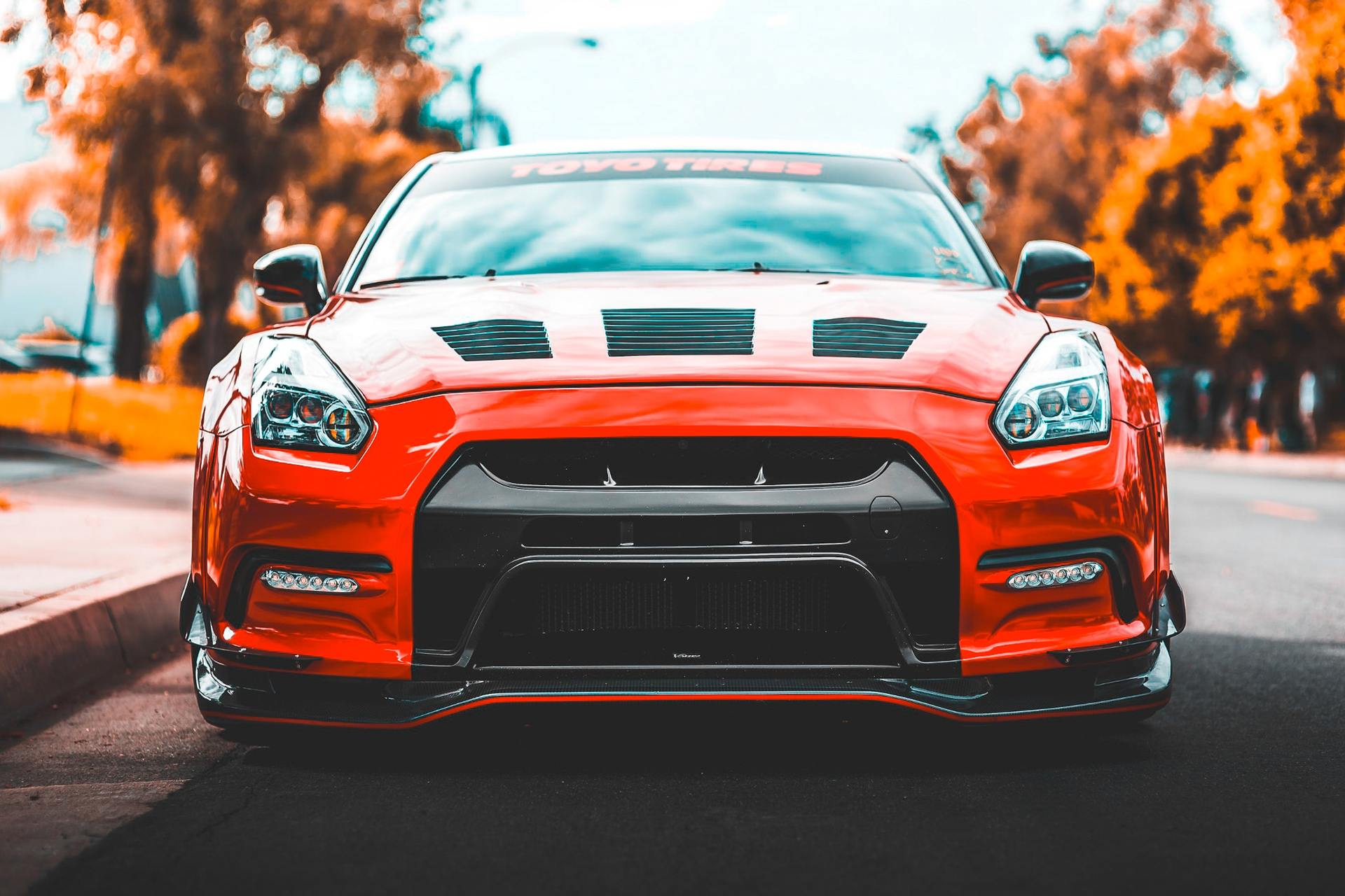 Red Nissan GT-R sports car with black accents parked on a road.