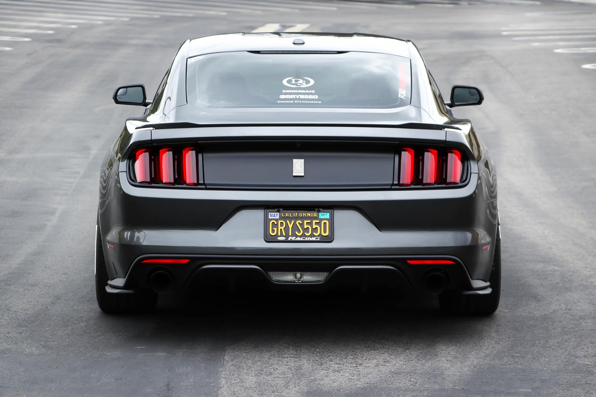 Rear view of a dark gray Ford Mustang with black accents and a California license plate.